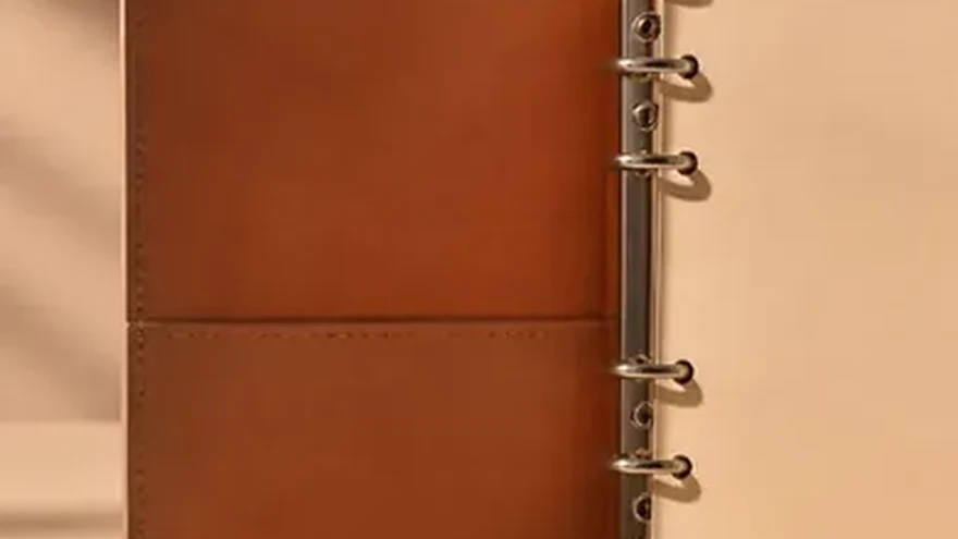 An open ring binder with tabbed dividers beside a magnifying glass