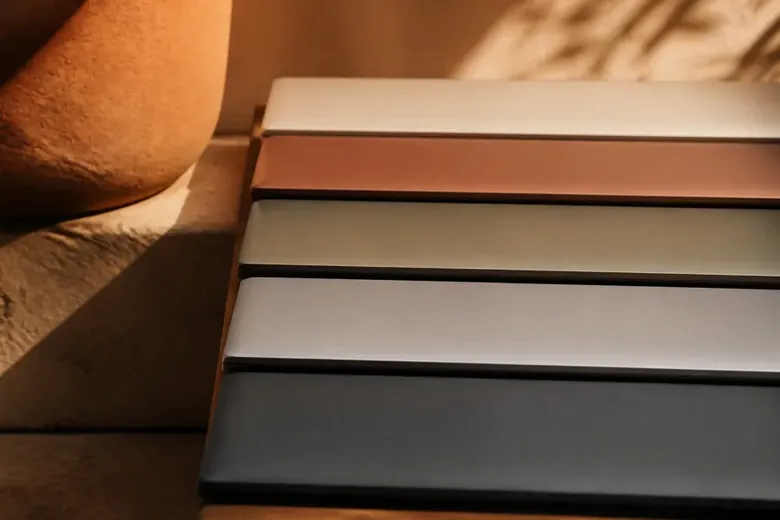Several distinct closed laptops arranged in a row on a table, each a different colour